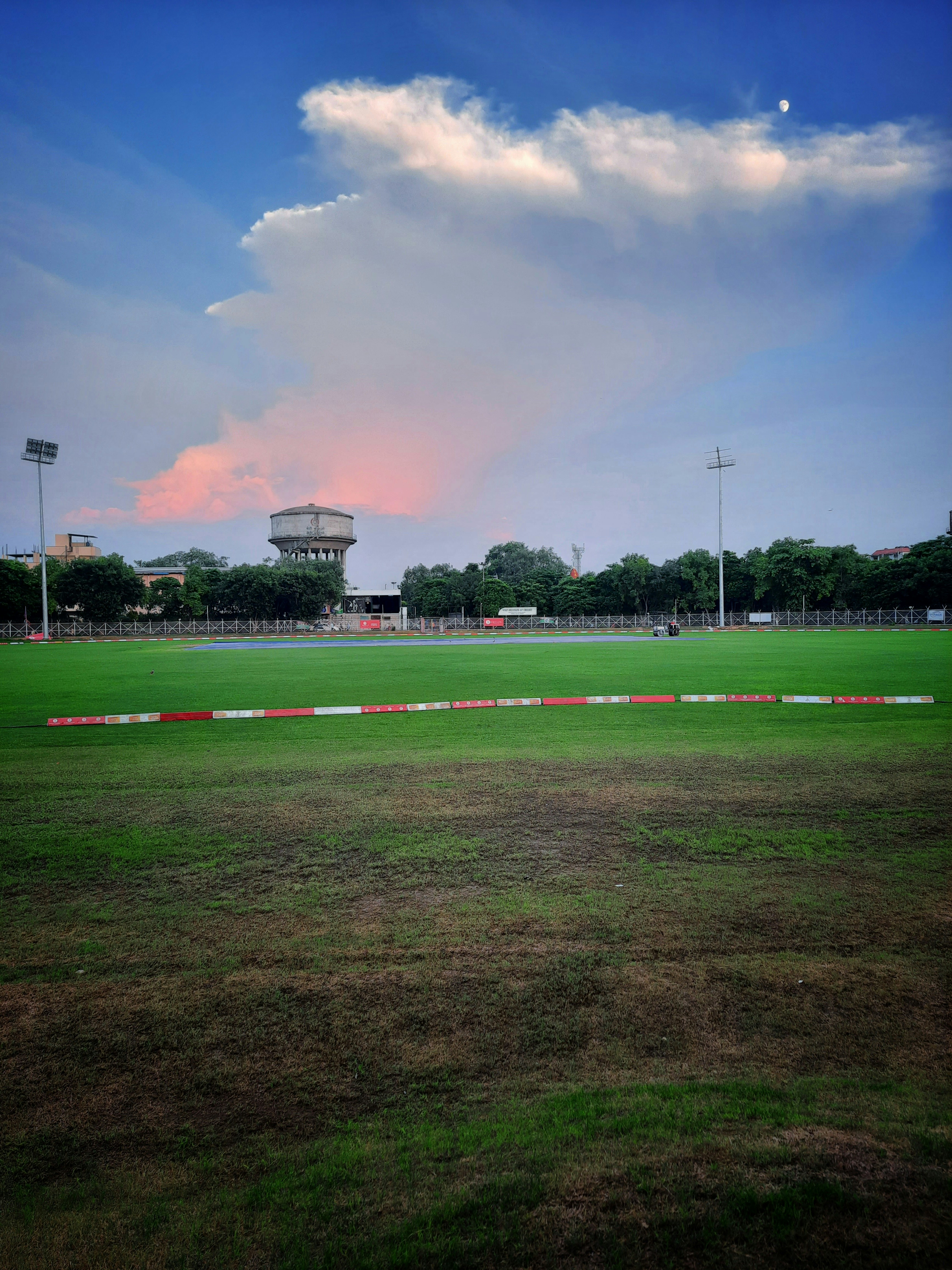 a field with a track and a tower in the background