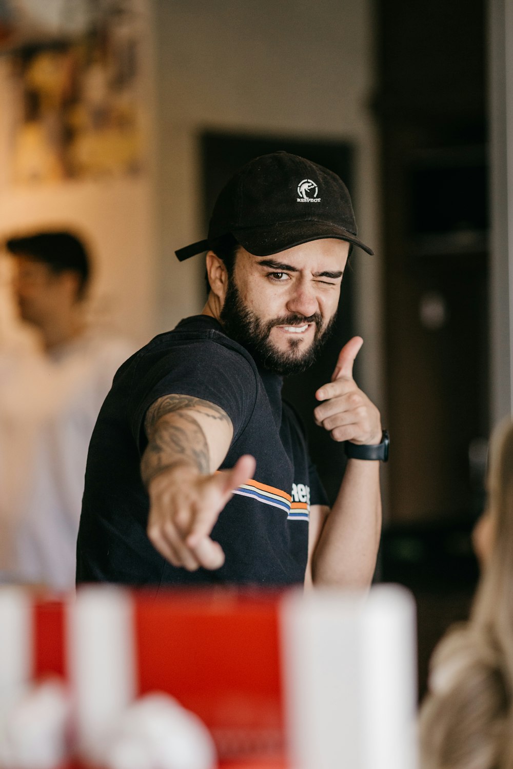 a man wearing a black hat and holding his thumb up