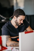 a man with a beard looking at a computer monitor