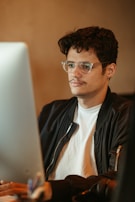 Person wearing blue light glasses while working on a computer in a cozy home office