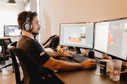 a man wearing headphones and sitting at a desk with a computer