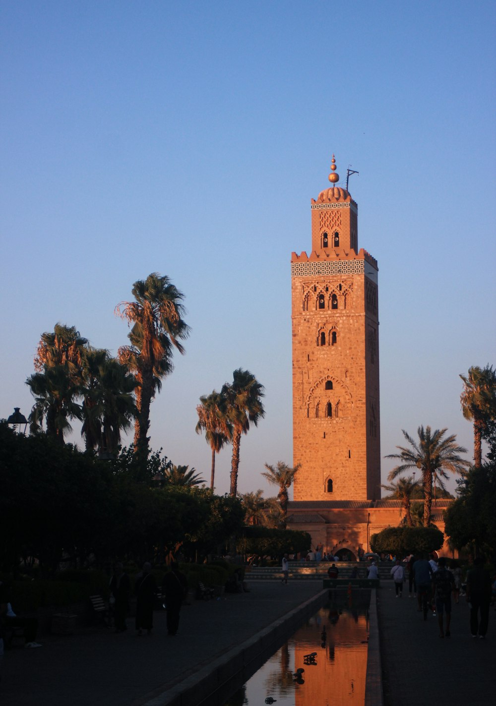 a tall tower with a clock with Koutoubia Mosque in the background