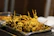 Close-up of sizzling kababs grilling over charcoal with vibrant spices sprinkled on top.