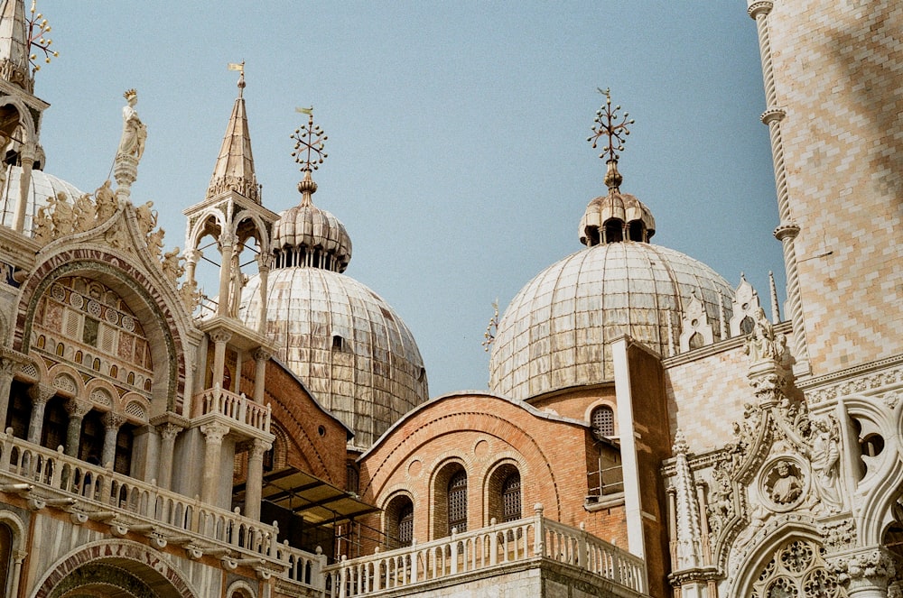 um grande edifício ornamentado com telhados abobadados com a Basílica de São Marcos ao fundo