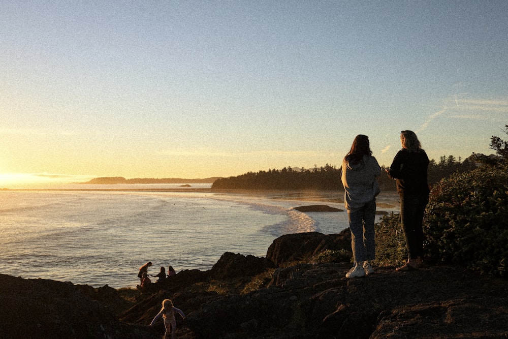 Un grupo de personas de pie en una playa rocosa mirando el agua