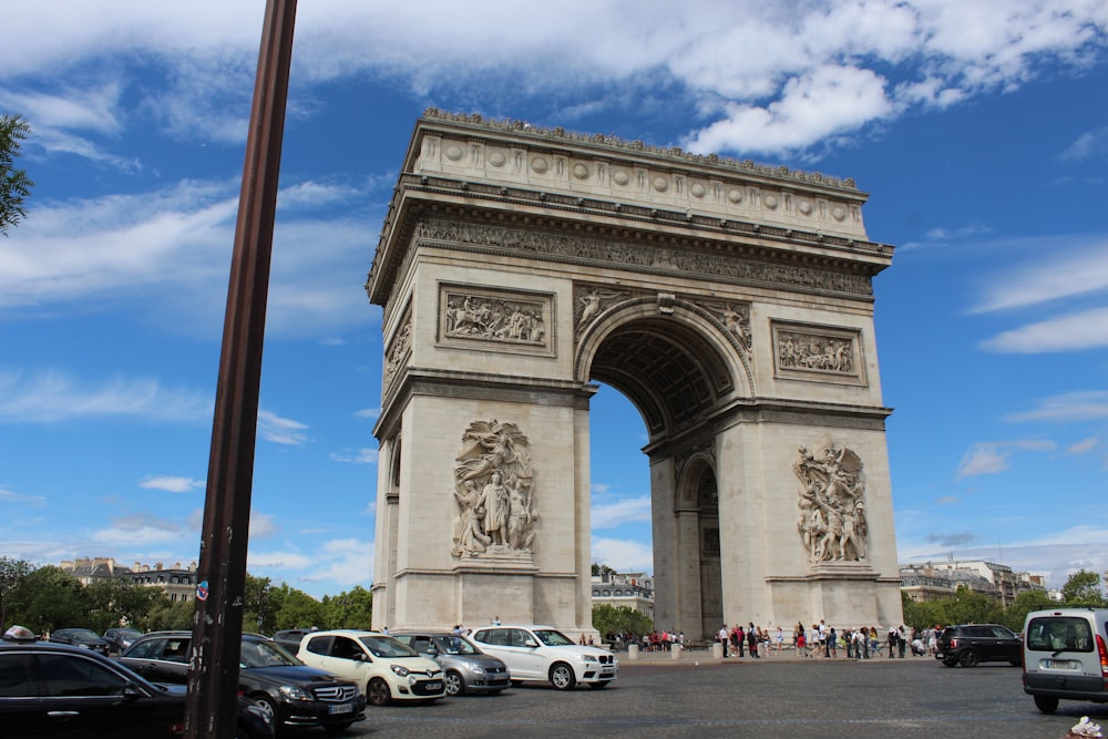 a large stone monument with a crowd of people in front of it with Arc de Triomphe in the background