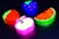Brightly colored erasers shaped like fruits, including a slice of watermelon, an apple, a strawberry, and a bunch of grapes, are placed against a dark background.