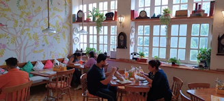 Warm interior of Koffee Hut café with friends enjoying coffee and meals around wooden tables.