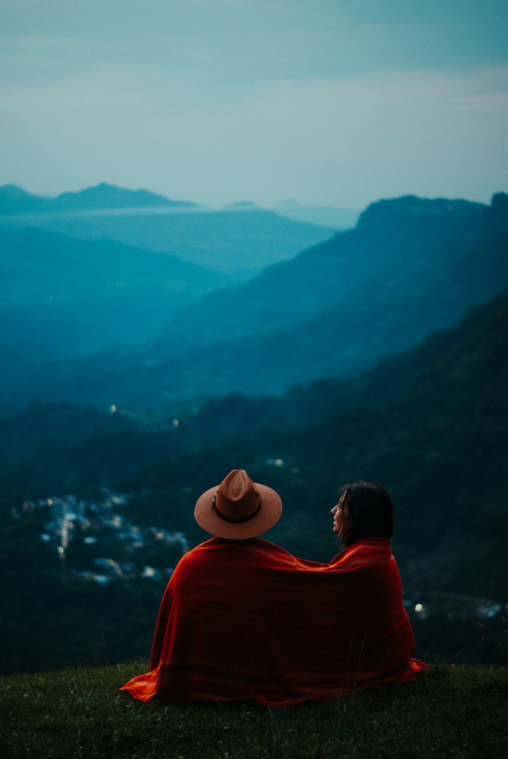 a person sitting on a hill looking at a body of water