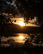 A warm-toned cinematic shot of a sunset over a quiet lake, filmed by infinity art.