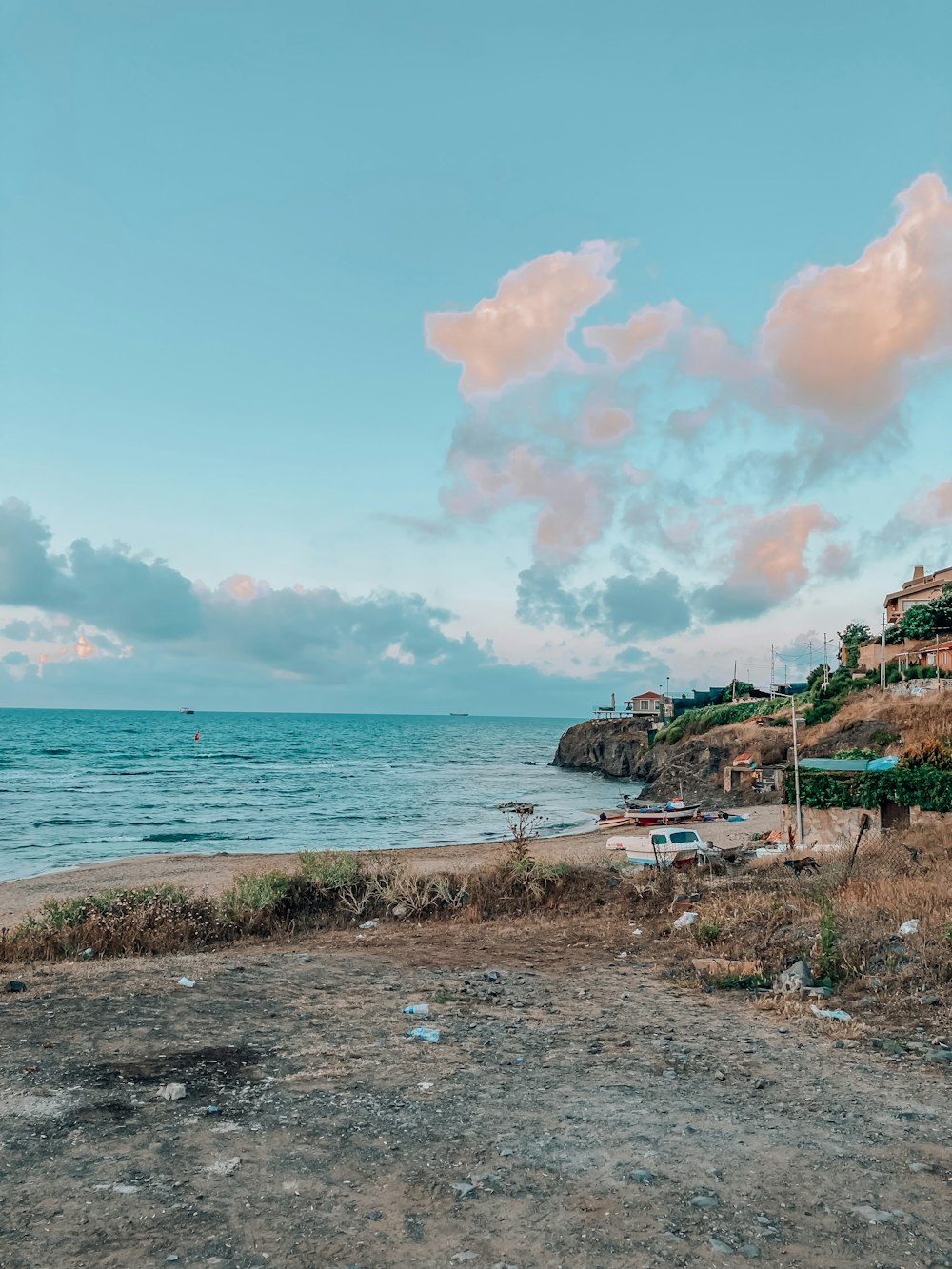 a beach with a body of water and a hill with buildings on it