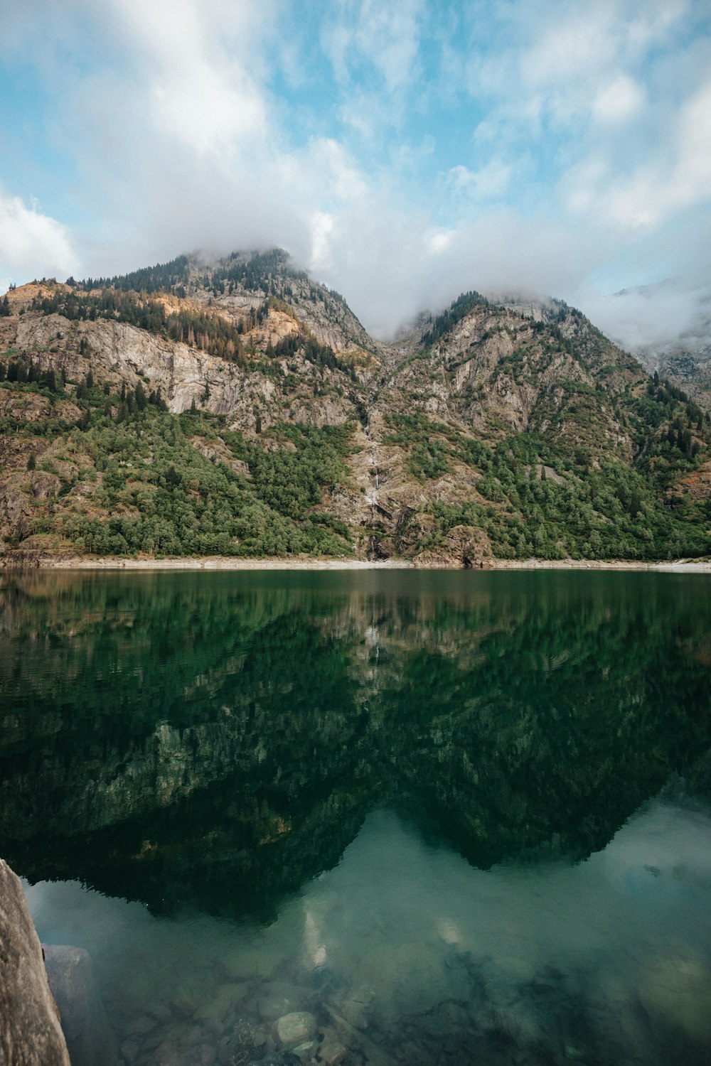 Un cuerpo de agua con árboles y montañas al fondo