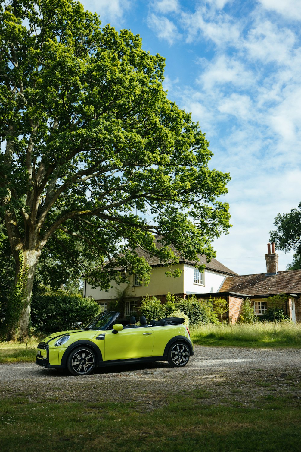 a yellow sports car parked in front of a tree and a house