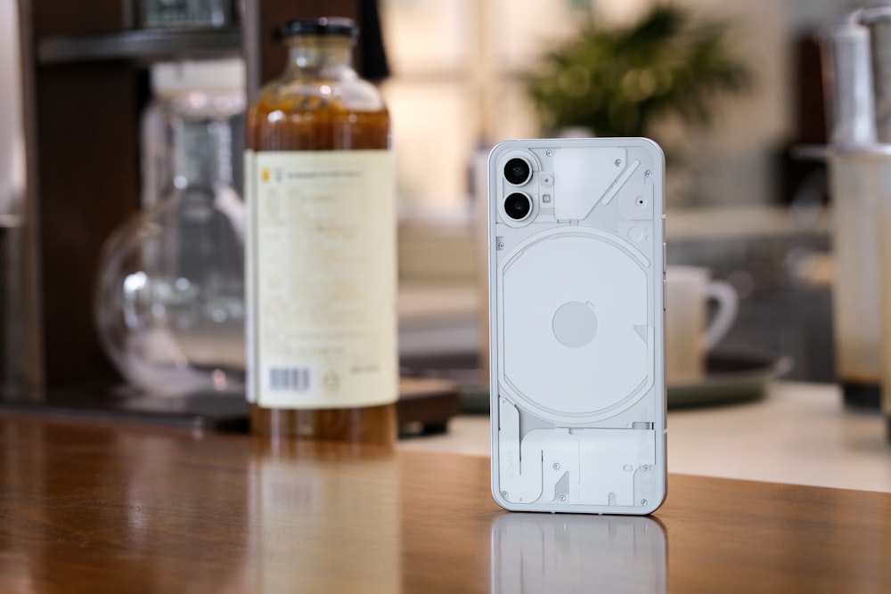 a white cell phone with a bottle of alcohol in the background