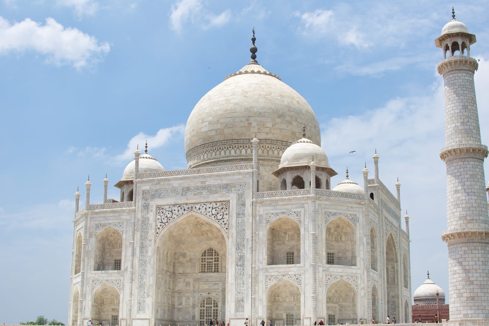 a large white building with domed roofs with Taj Mahal in the background