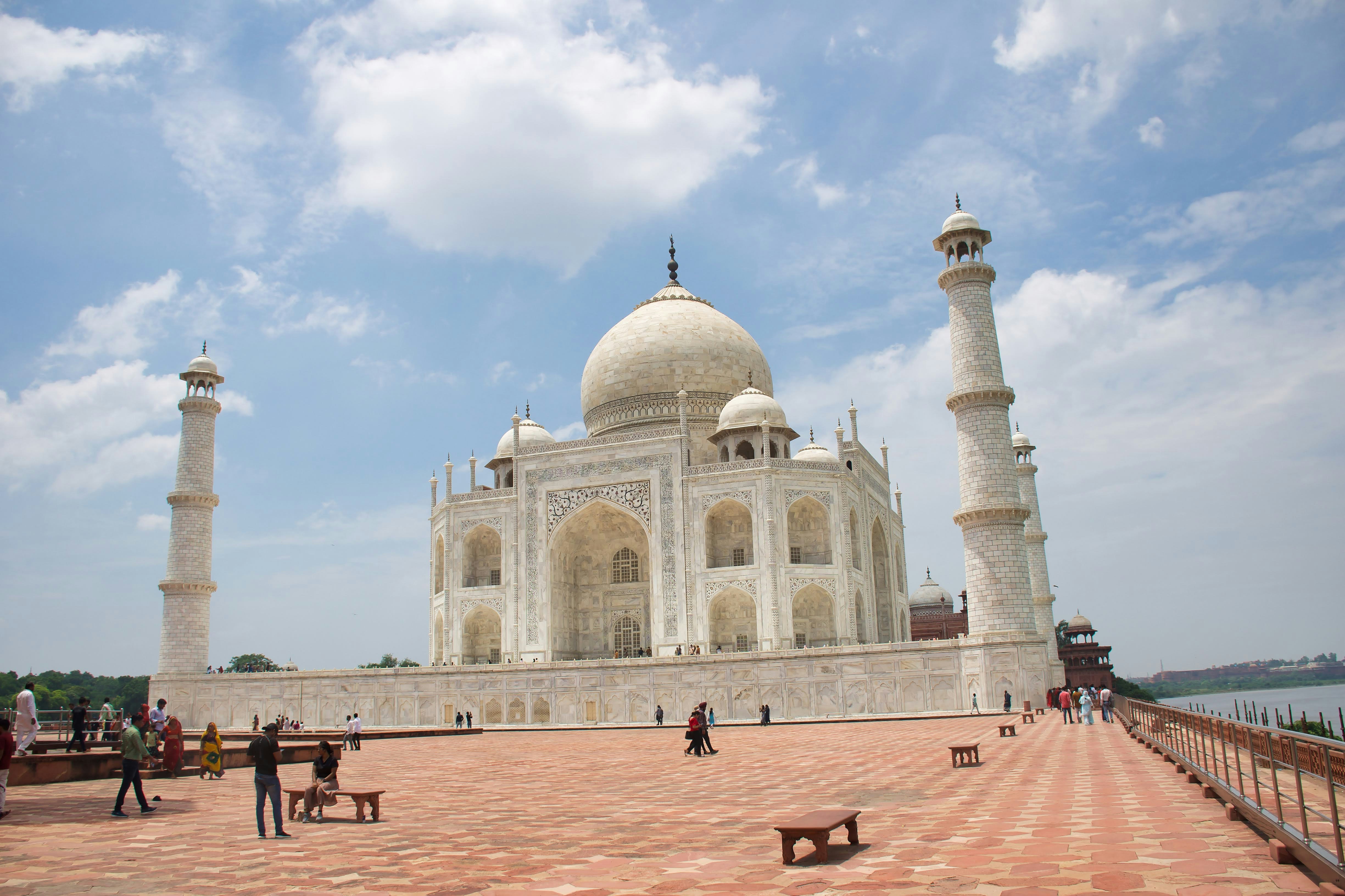 a large white building with a domed roof and towers with Taj Mahal in the background