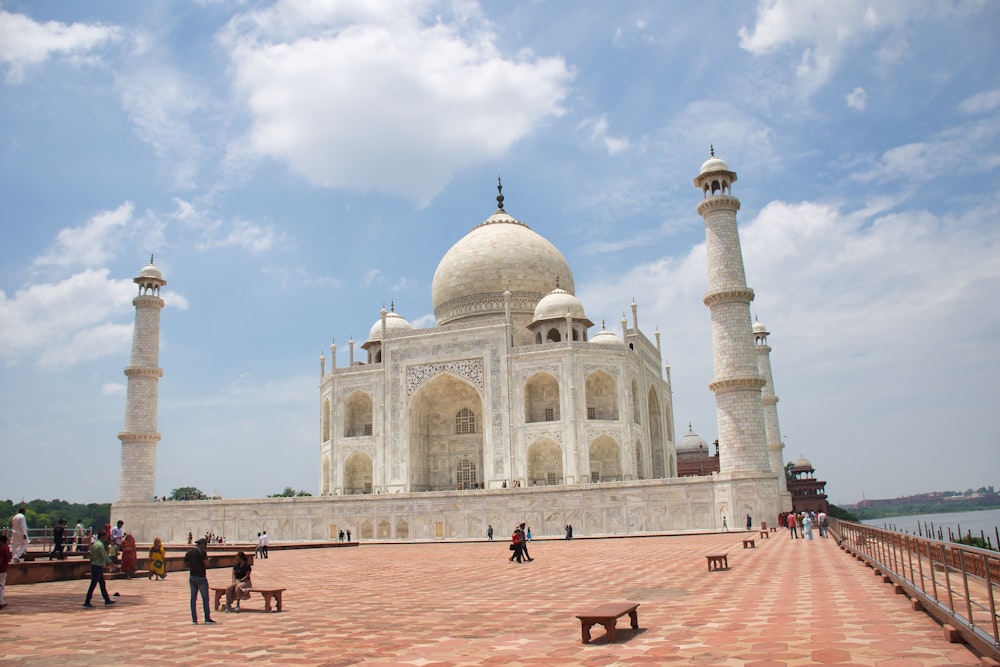 a large white building with a domed roof and towers with Taj Mahal in the background