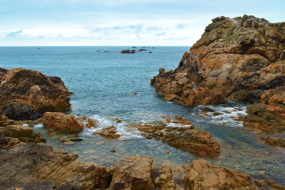 a rocky beach with a body of water in the background