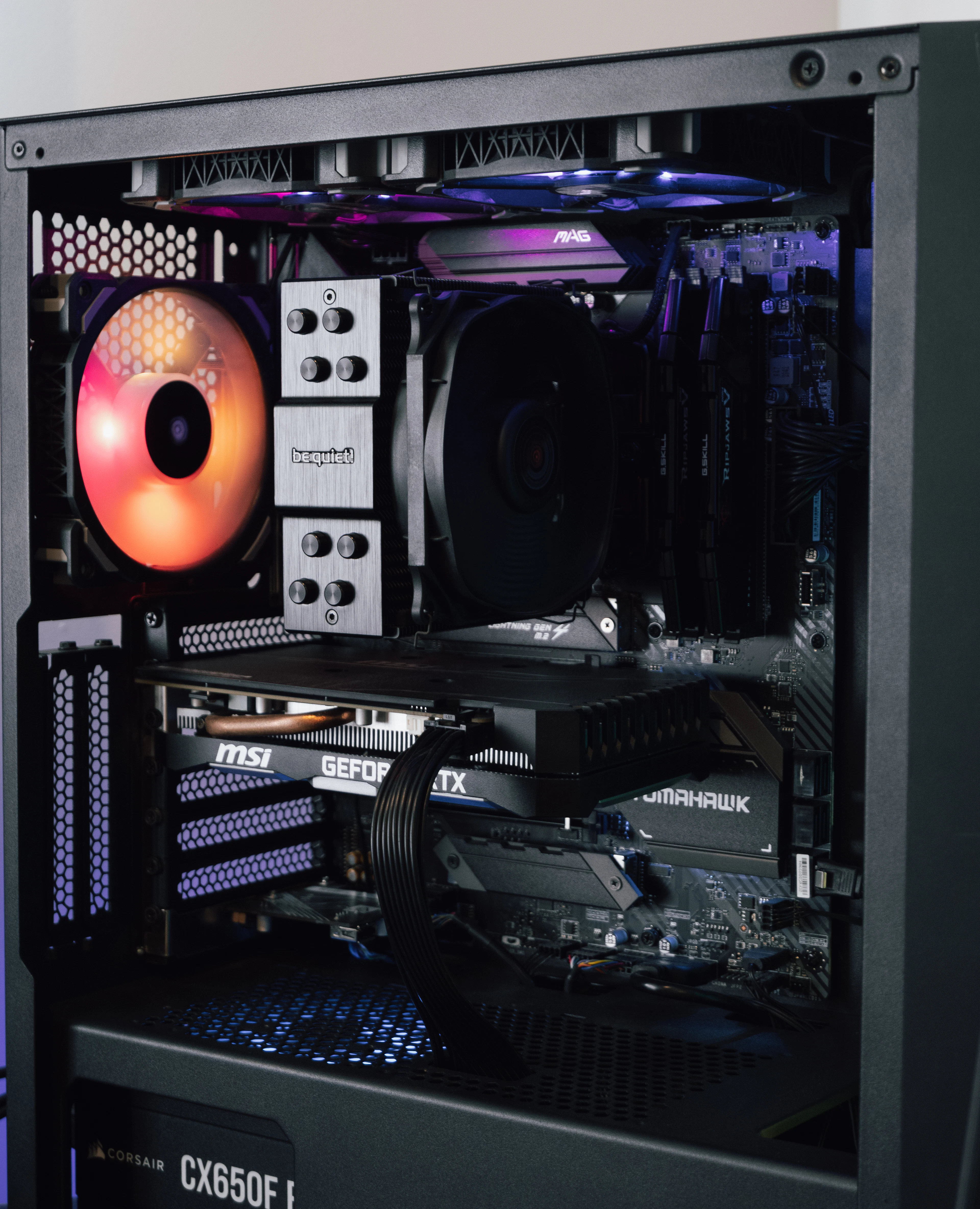Interno di un PC gaming con ventola illuminata di arancione, scheda video e alimentatore in vista