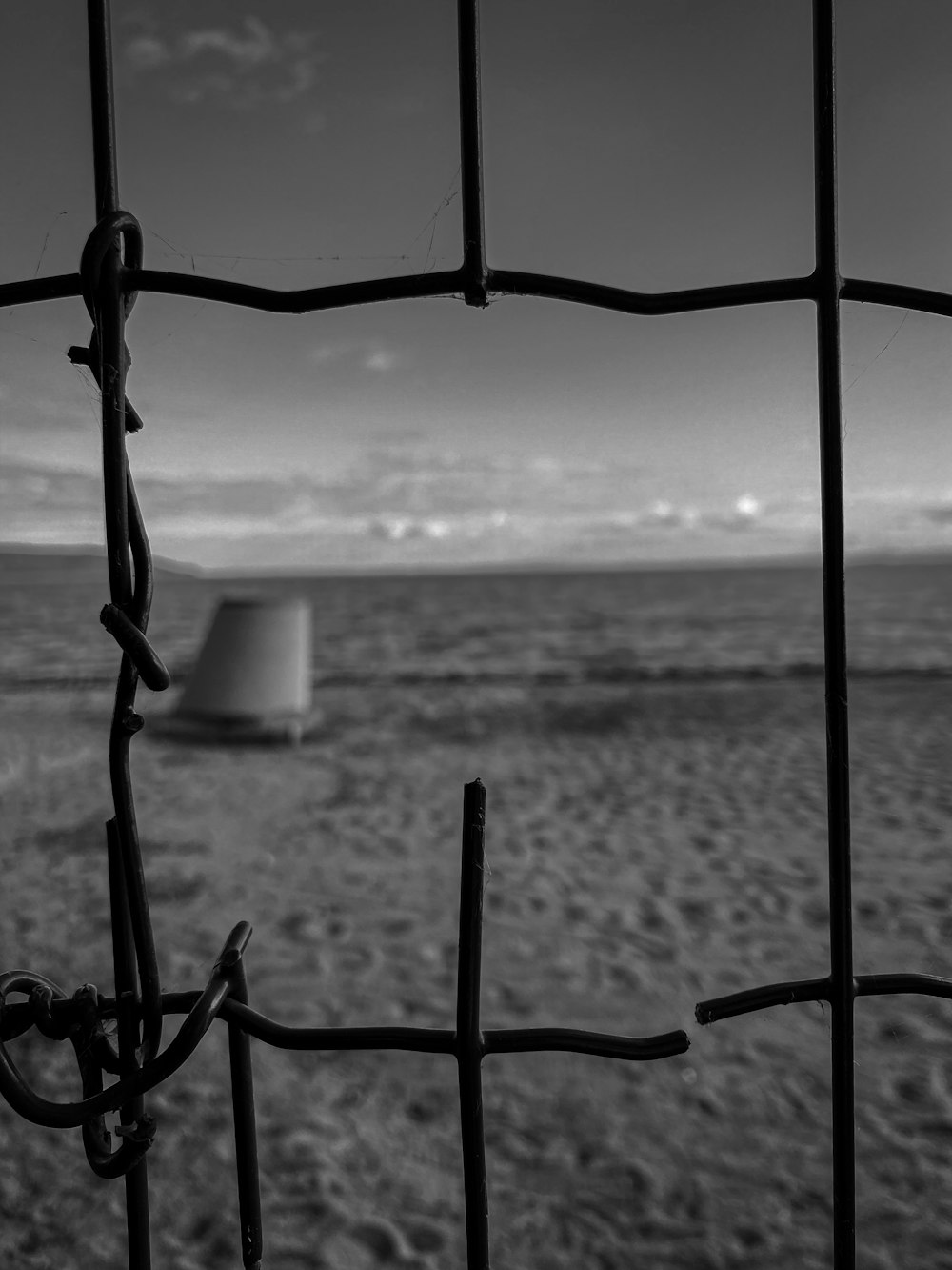 a black and white photo of a fence and a beach