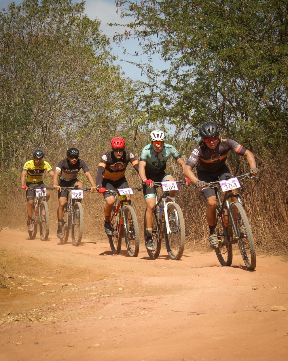 a group of people riding bikes on a dirt road