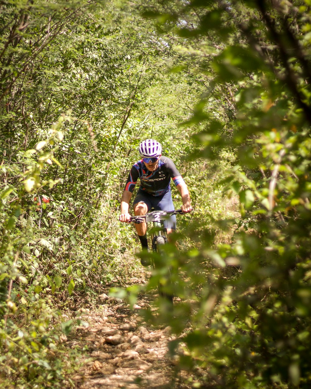 a person riding a bike on a trail surrounded by trees