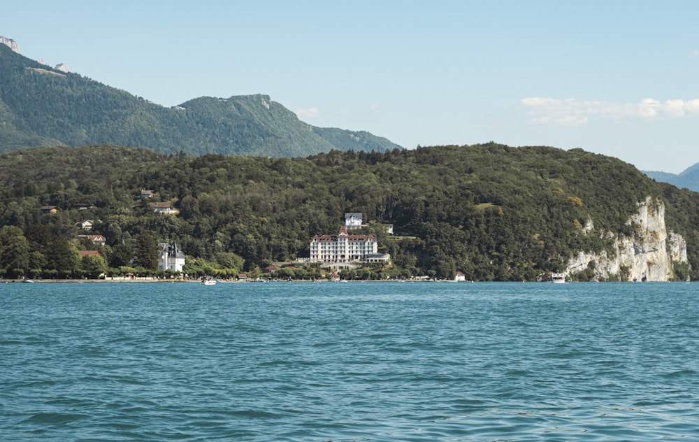 a body of water with a building on the shore and mountains in the background