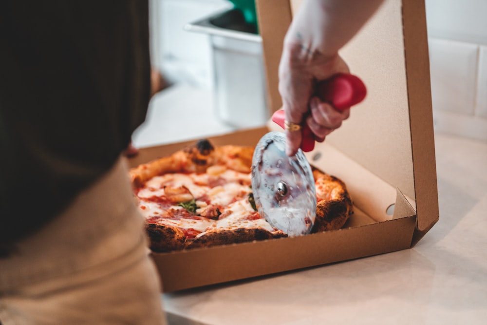 a person slicing a pizza