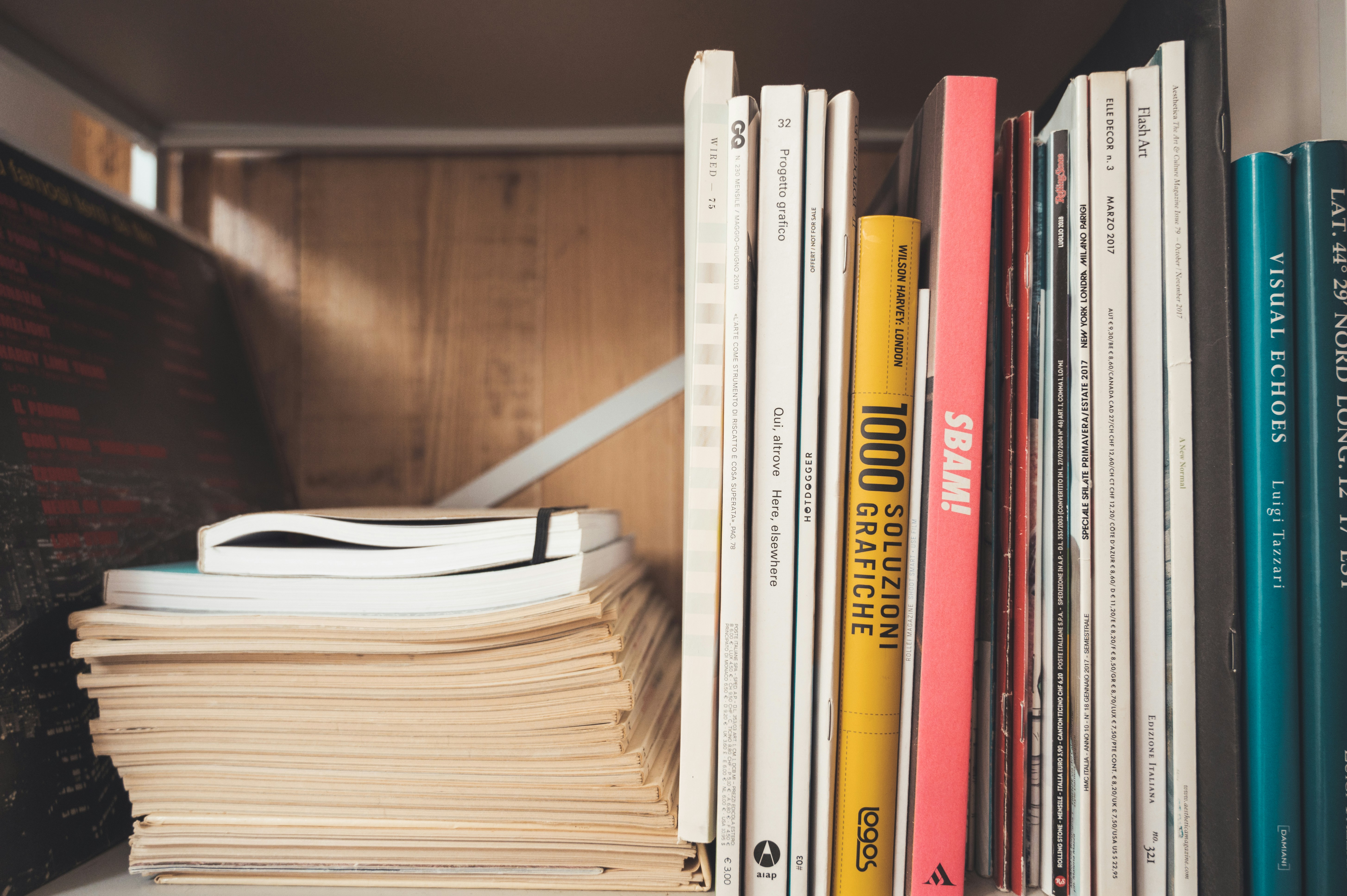 Stack of books with colorful spines on dark wooden surface