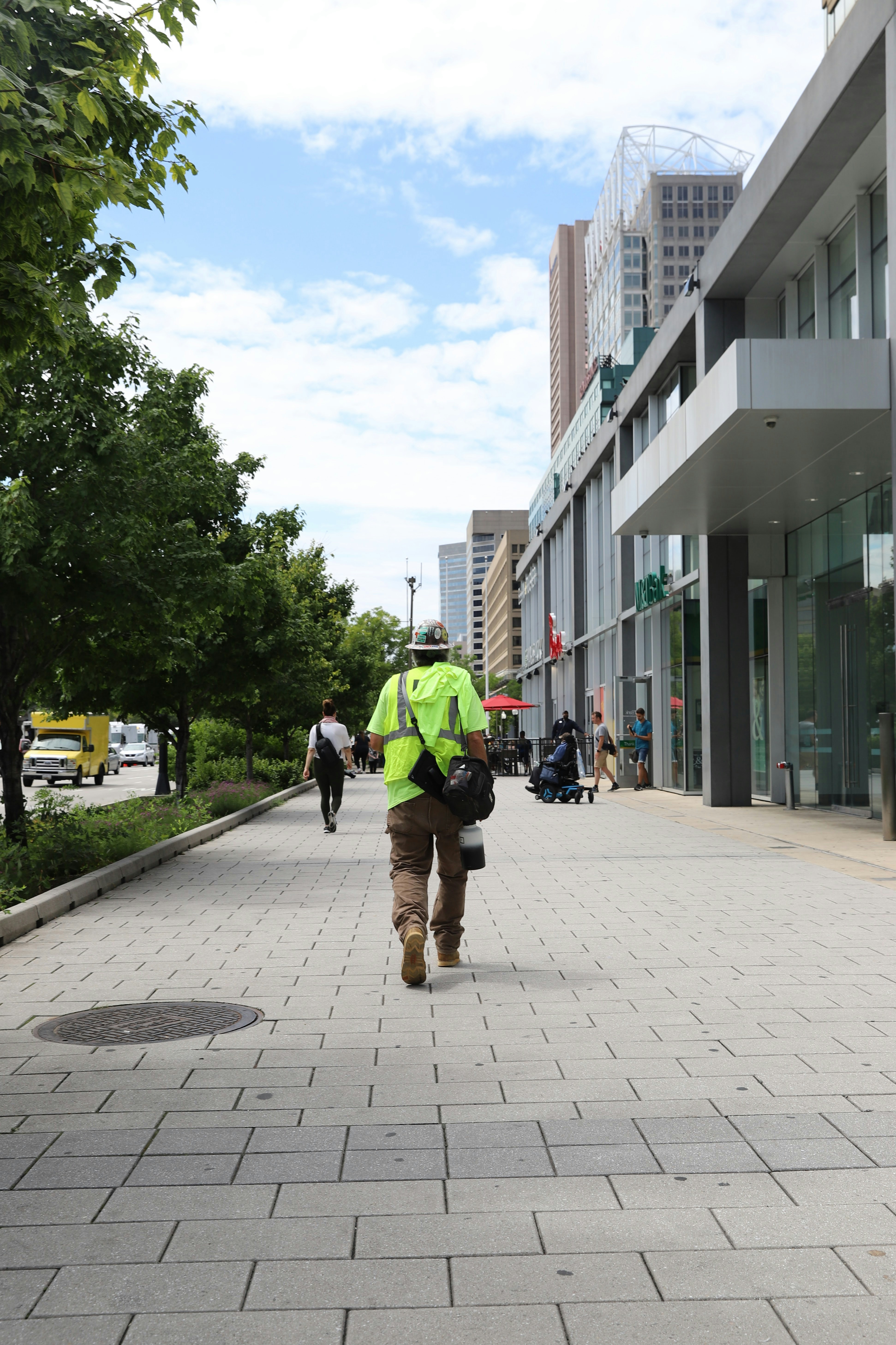 Eine Person in einer gelben Weste, die einen Bürgersteig entlang geht