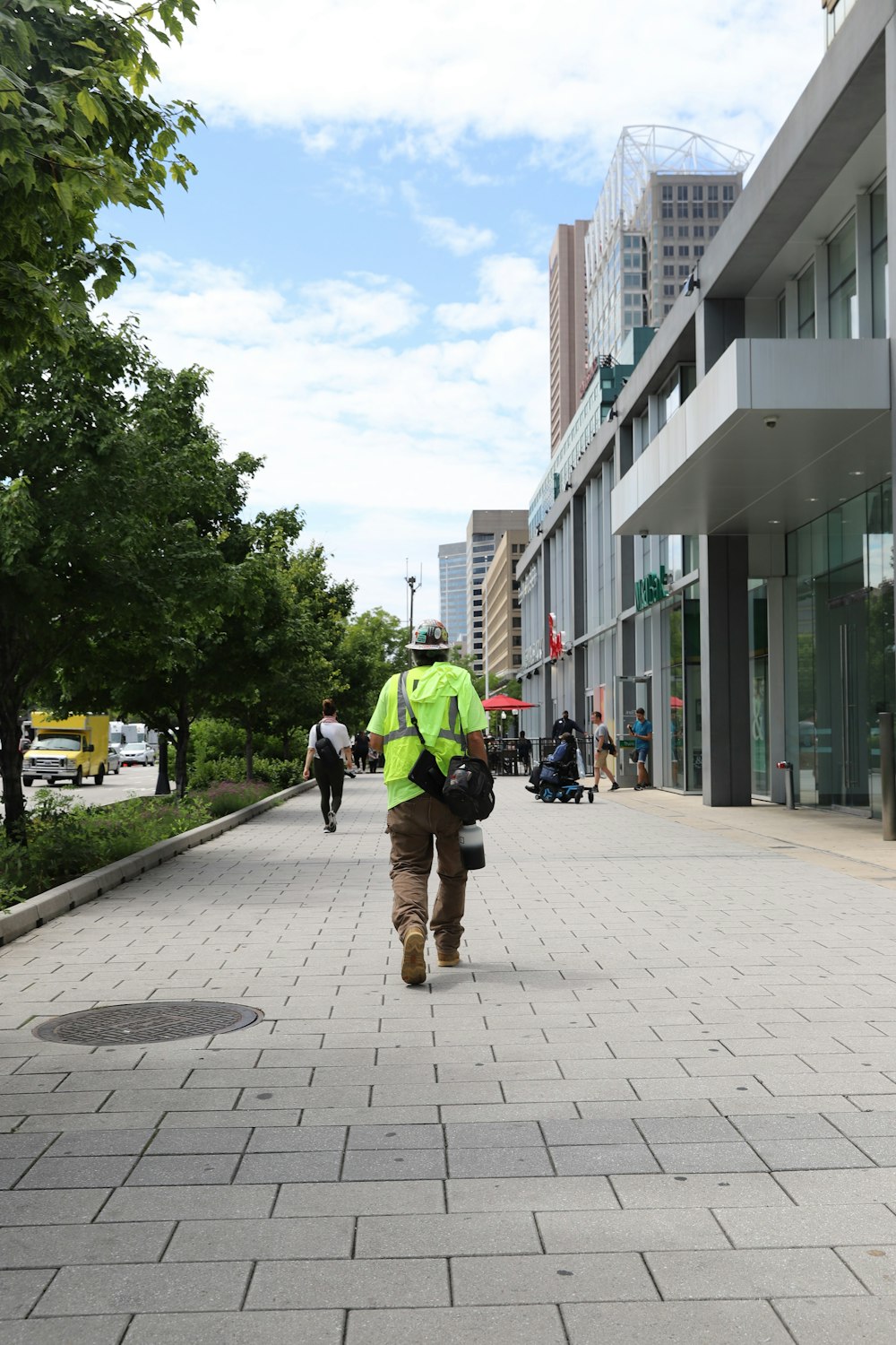 a person in a yellow vest walking down a sidewalk