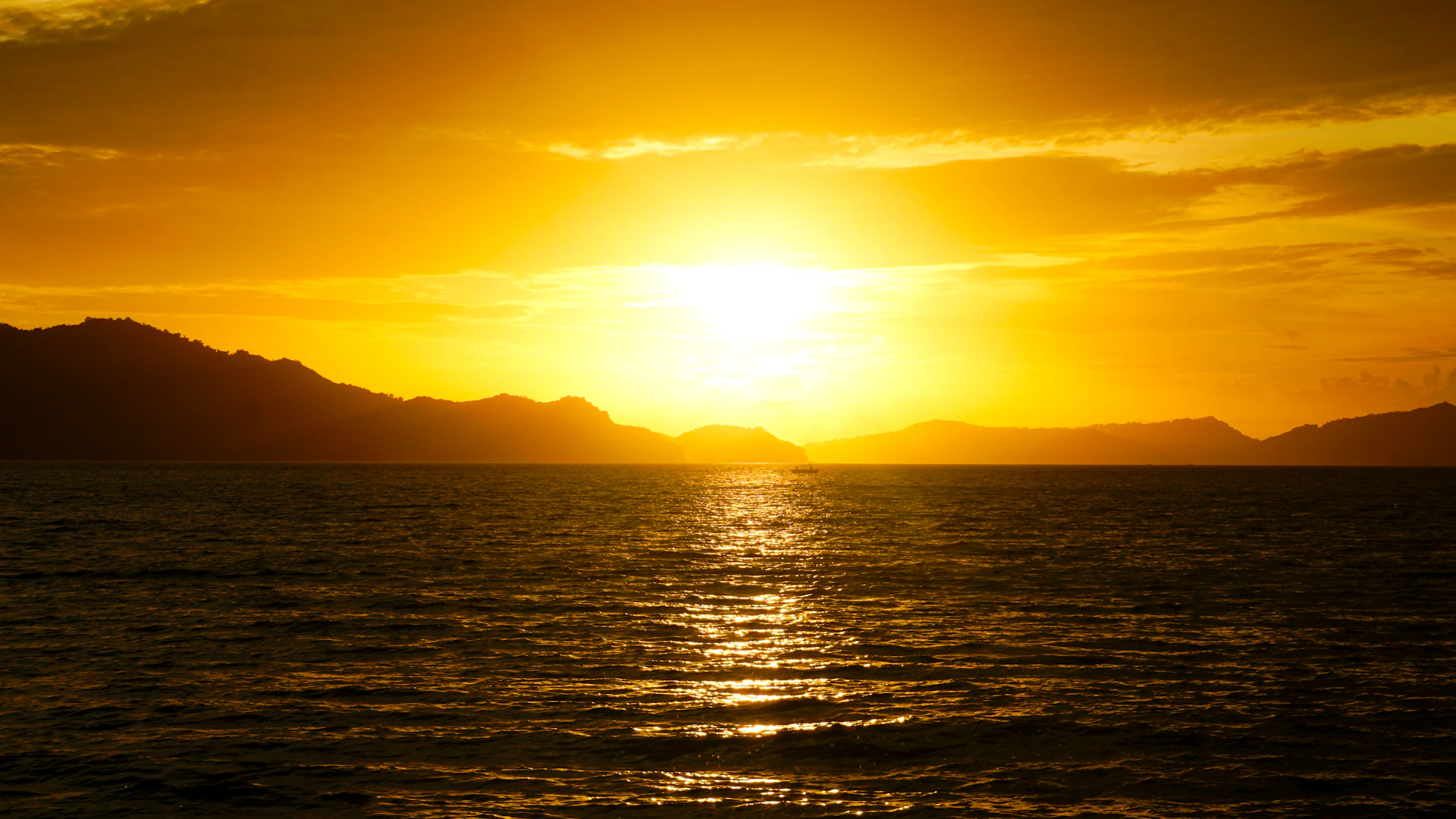 A vibrant sunset over lush tropical mountains, with a winding river reflecting golden light.