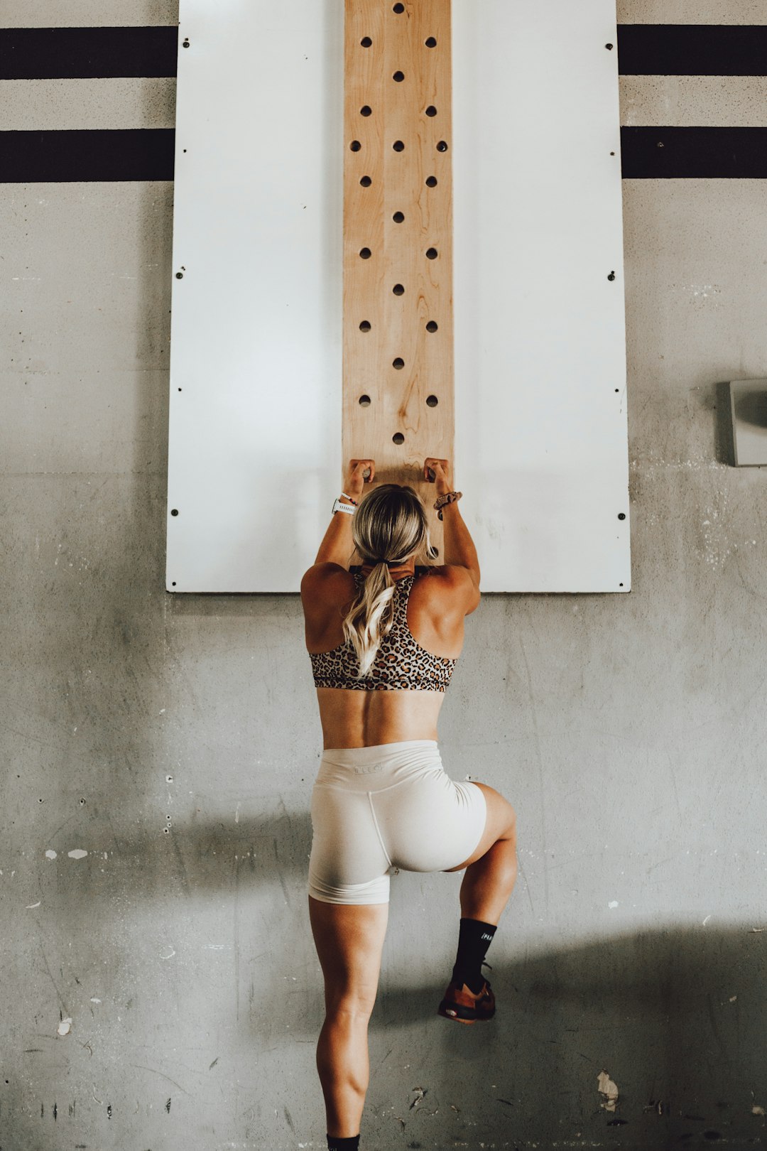 Girl working out on peg board in CrossFit gym