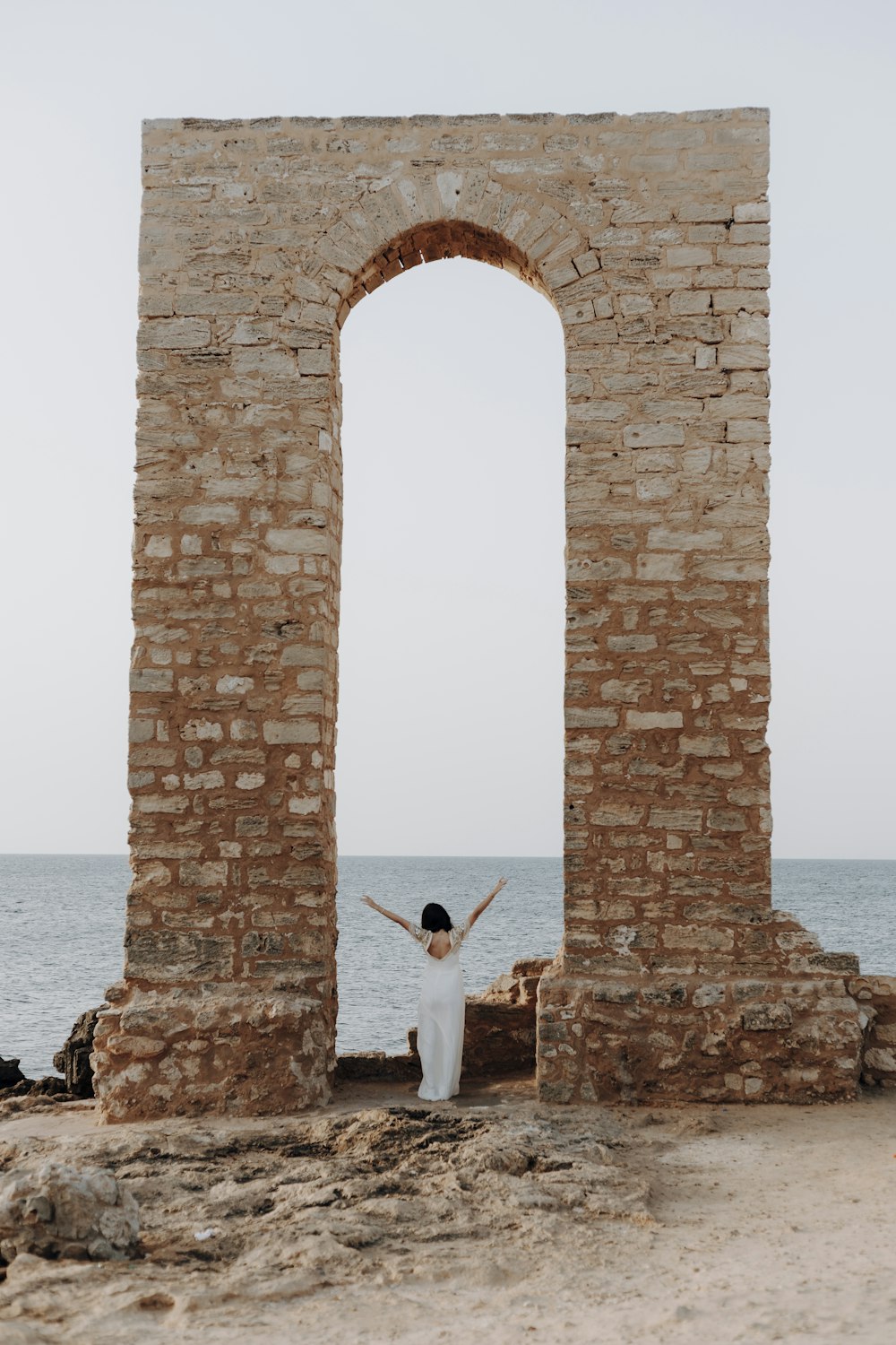 a man and woman standing in front of a large stone arch