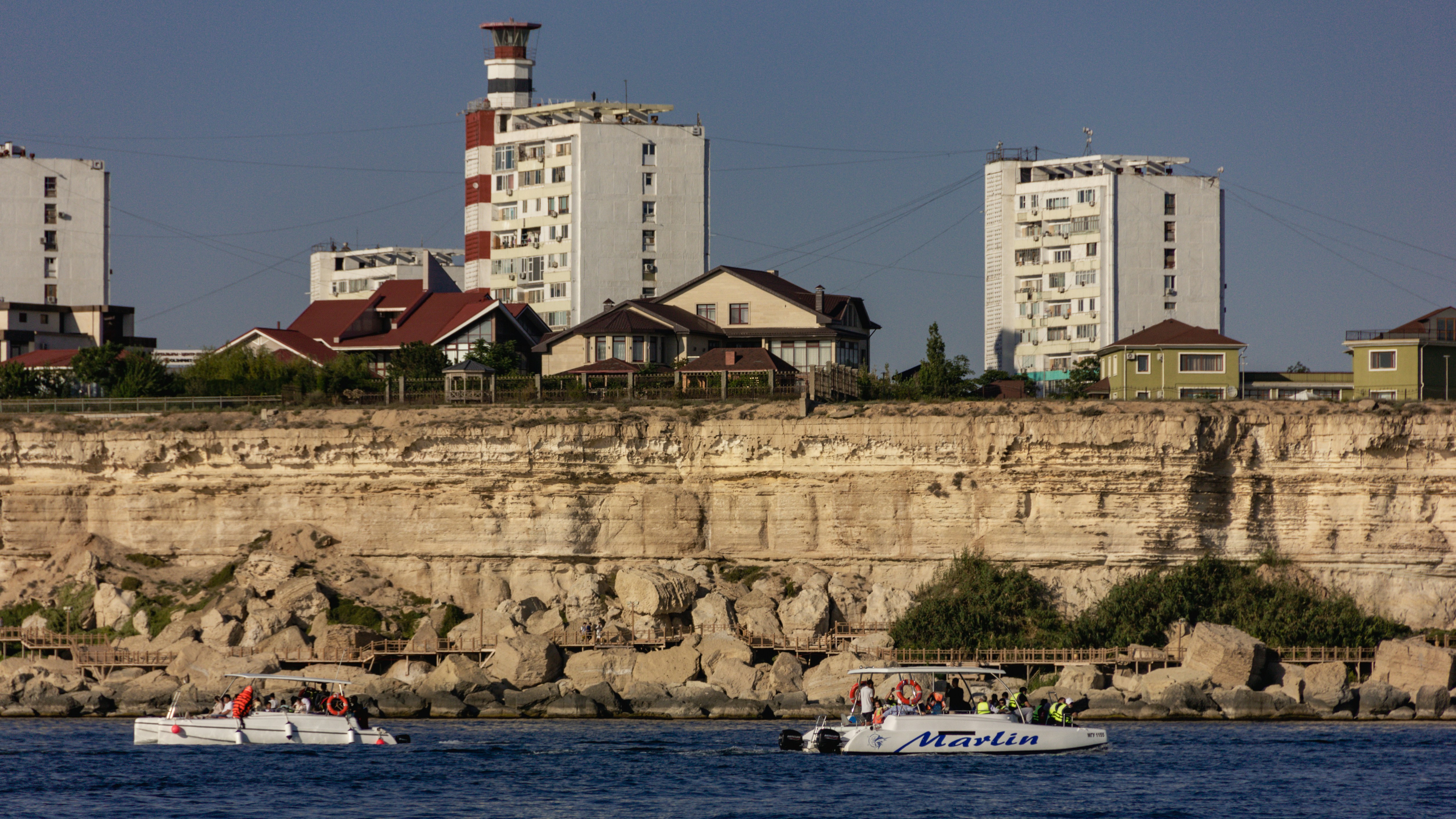 Group of boats on a rocky shore near an iconic lighthouse by the sea