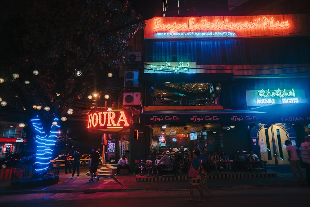 a group of people outside of a building with neon signs