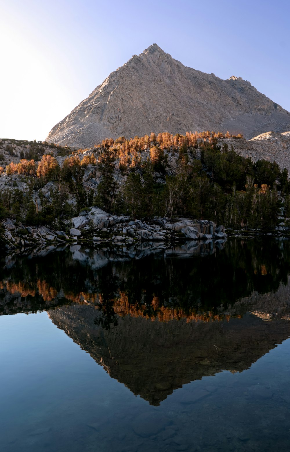 a mountain with trees and a body of water below