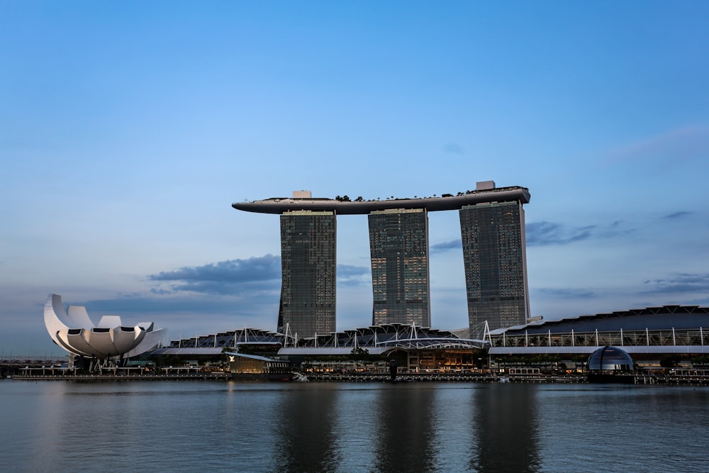a large building with a large white satellite dish in front of it with Marina Bay Sands in the background