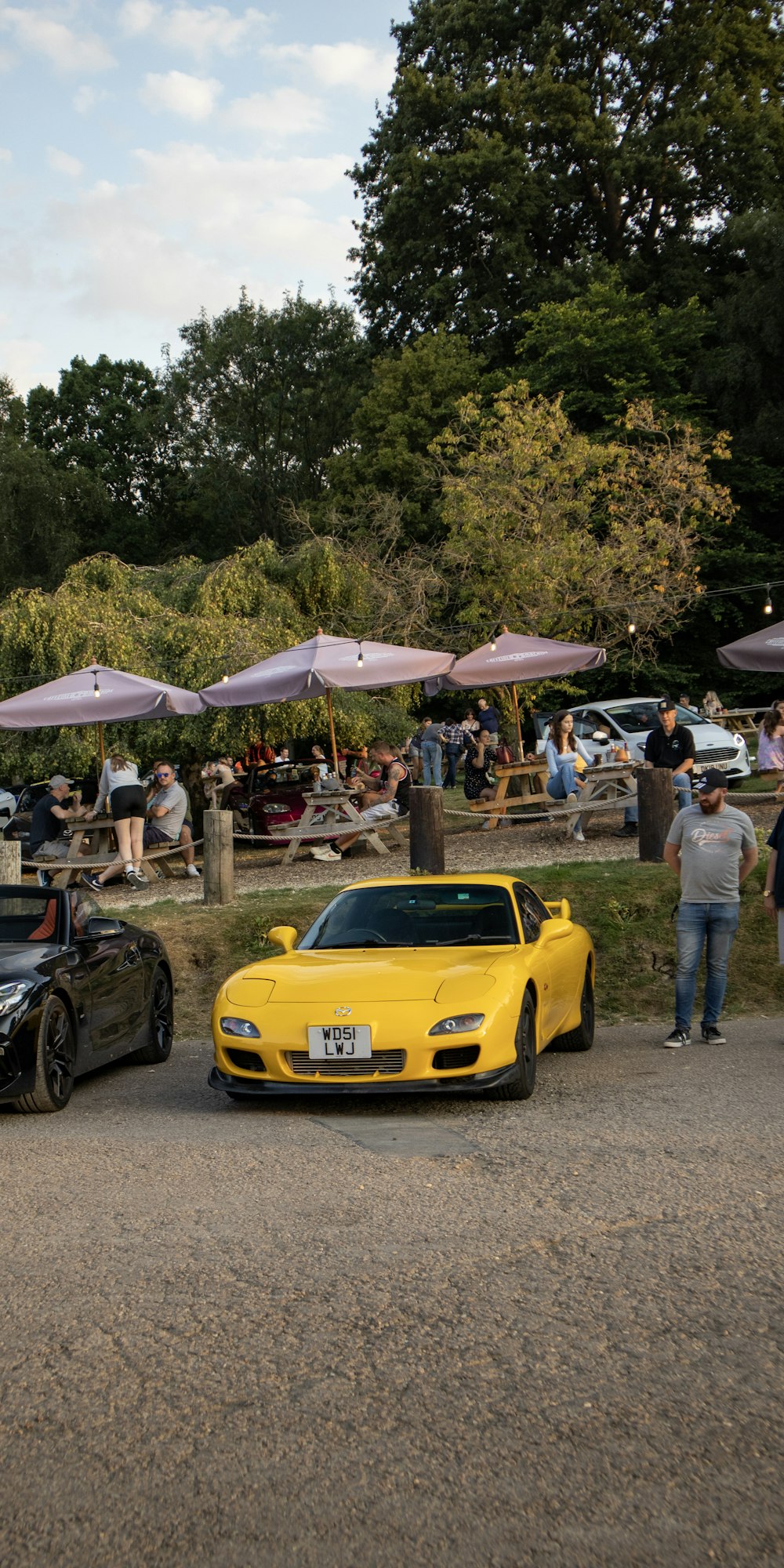 a yellow sports car parked in front of a crowd of people