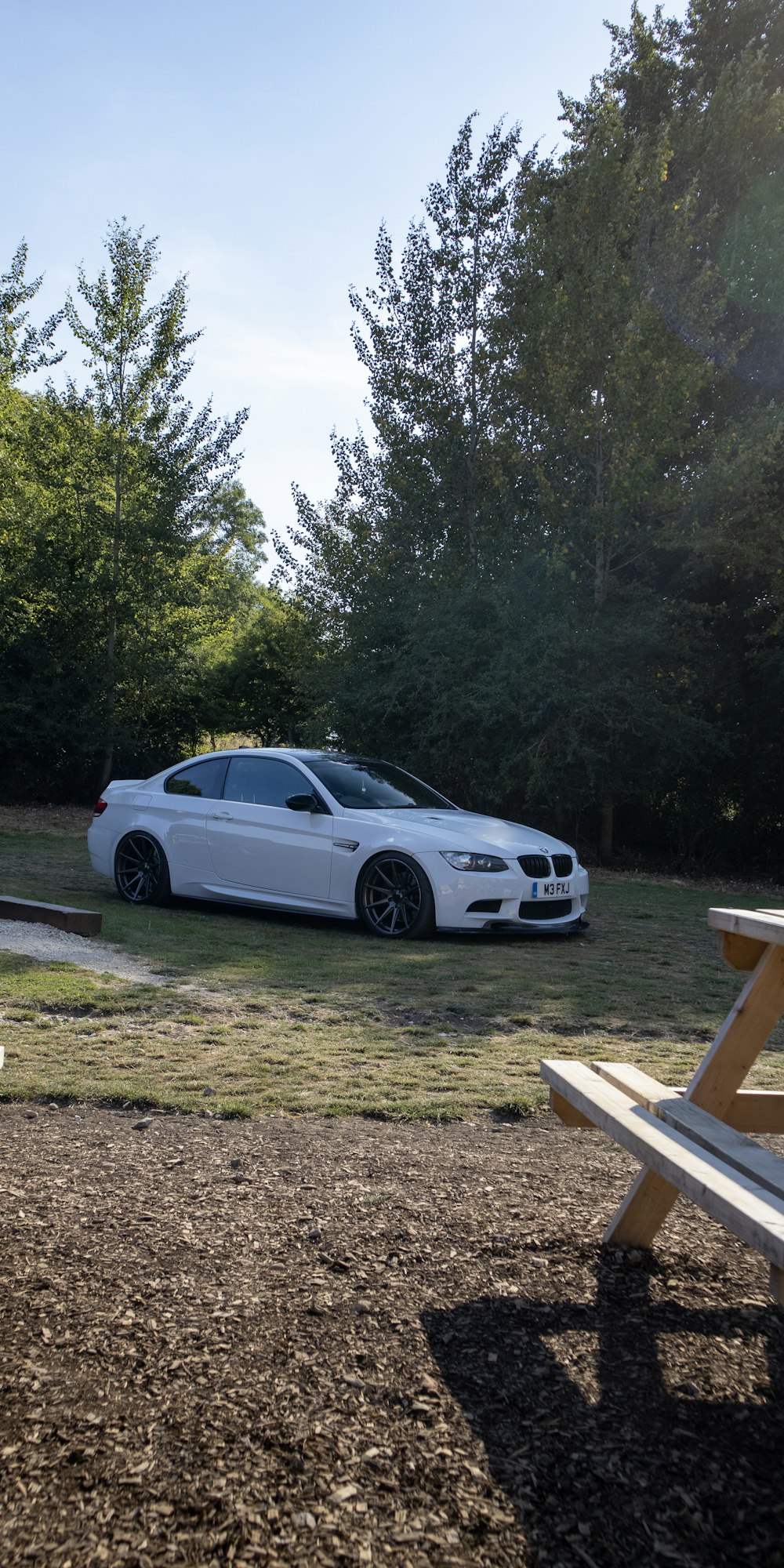 a white car parked on grass near trees