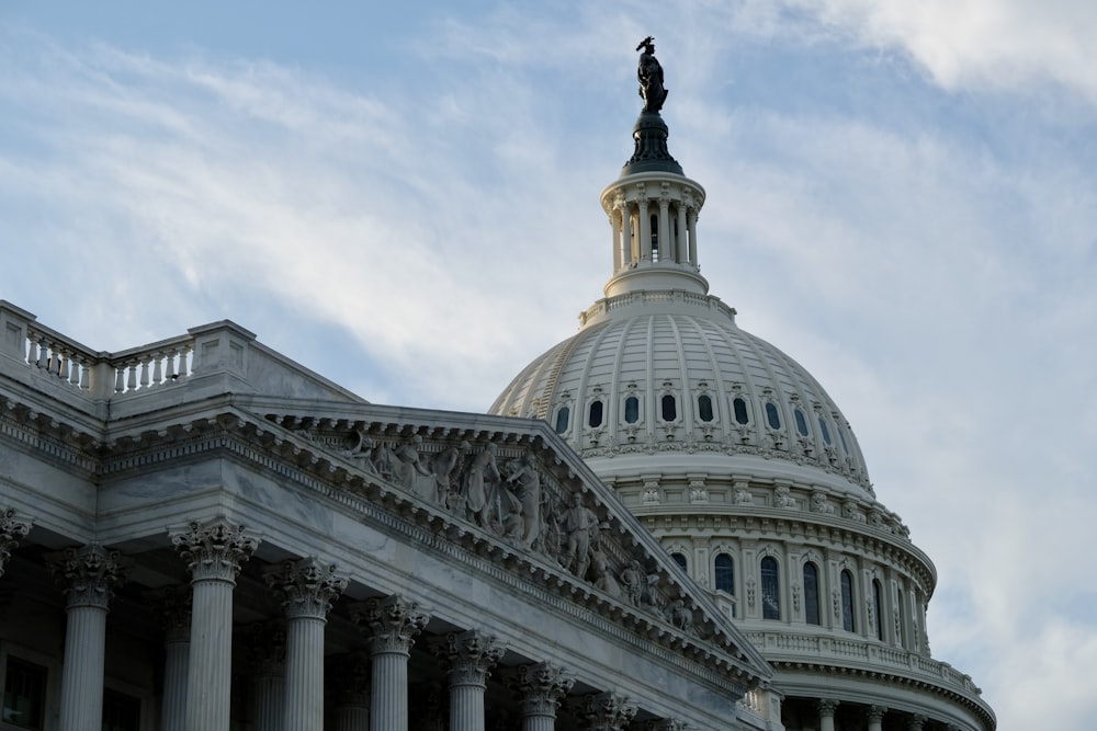 a large white building with a statue on top with United States Capitol in the background