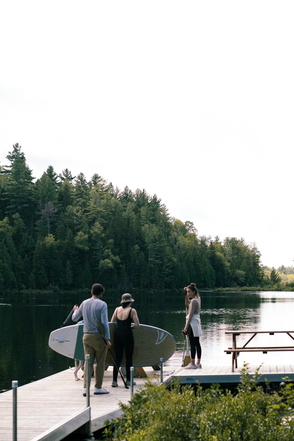a group of people standing on a dock with their surfboards