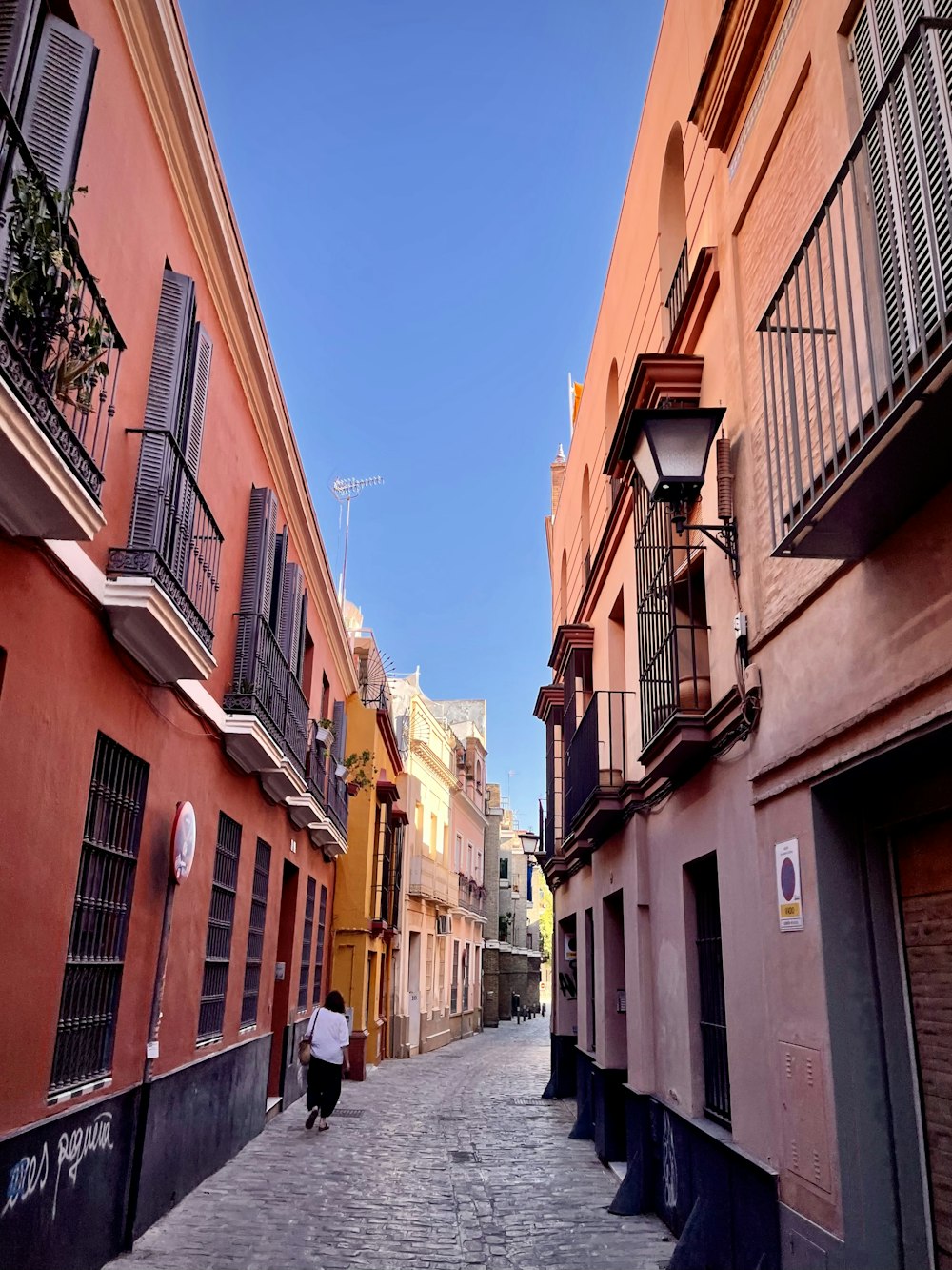 a person walking down a narrow street between buildings