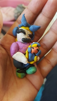 Close-up of hands holding a small, colorful 3D printed figurine