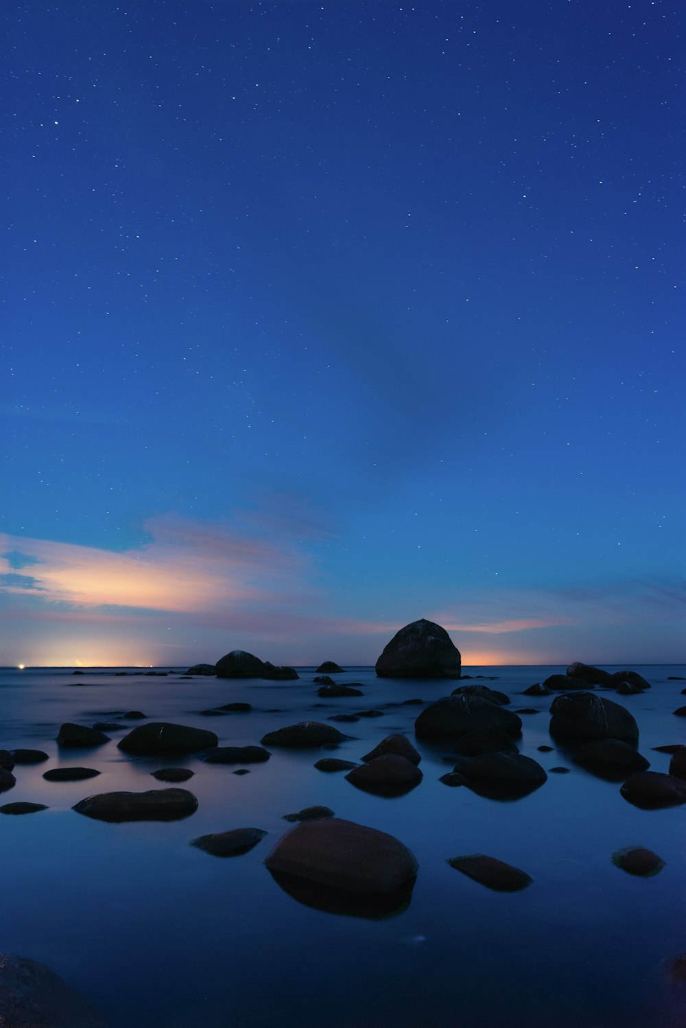 a body of water with rocks and a blue sky with stars