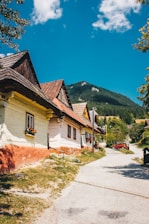 A cozy Bulgarian village street lined with traditional houses under a bright blue sky.