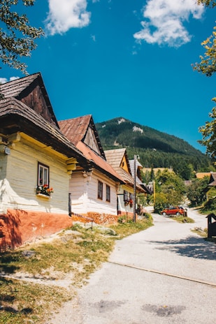 A cozy Bulgarian village street lined with traditional houses under a bright blue sky.