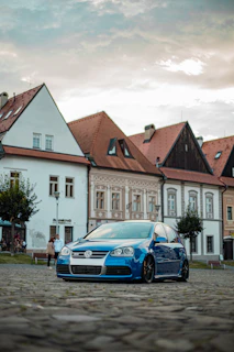 Compact city car in vibrant blue color parked on a cobblestone street
