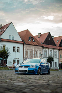 Compact city car in vibrant blue color parked on a cobblestone street