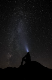 a person sitting on a mountain looking at the stars in the sky